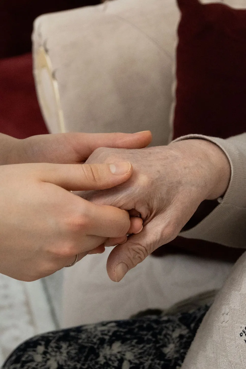 A younger hand gently holding an older person's hands — care and compassion