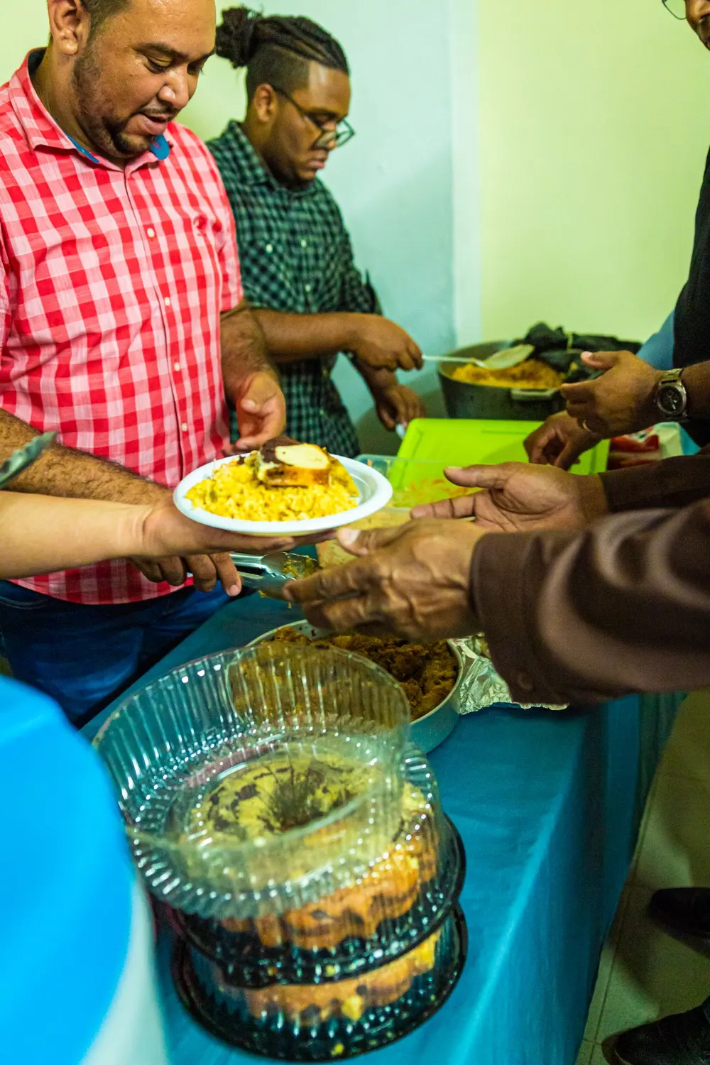 A shared community meal — a plate of food passed from hand to hand